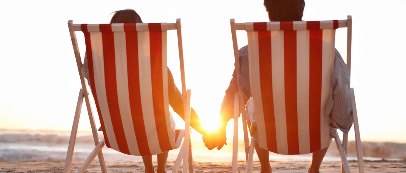 zwei Personen auf Strandstühlen halten ihre Hand