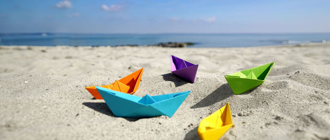 bunte Papierboote an einem Strand